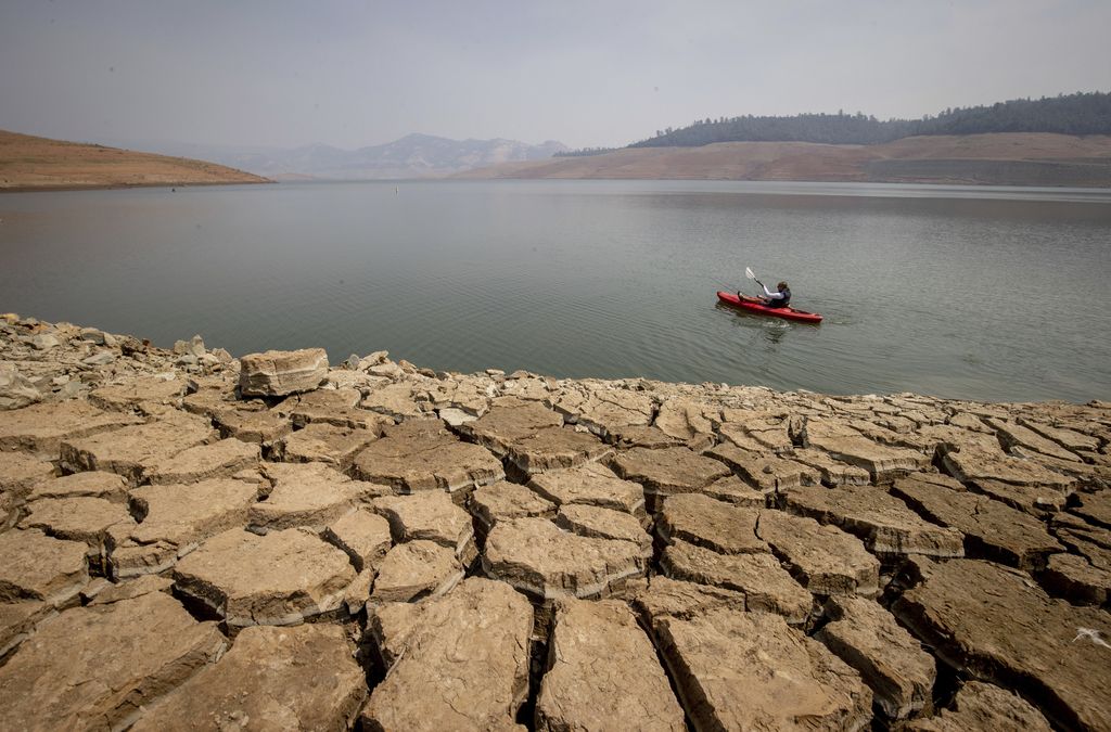 A kayaker fishes in Lake Oroville as water levels remain low due to continuing drought conditions in Oroville, Calif., Aug. 22, 2021. (AP Photo/Ethan Swope)