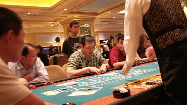 Customers are seen around the table of one of the main gaming floors of the Venetian casino on May 9, 2008 in Macau. The Venetian is presented as world's largest casino-resort, a gaudy mix of baccarat, shops and Venetian canals, opened in August, 2008 aiming to accelerate Macau's heady transformation from gambling haven to Asia's top entertainment draw. The 2.4 billion-USD resort, built on a spit of reclaimed land called the Cotai Strip, seeks to capitalise on the casino boom by getting the millions of visitors to stay for more than just a turn at the tables. With 3,000 hotel rooms, a theatre, a 15,000-seat stadium and 350 shops, as well as the gambling arenas, it is the anchor of the Cotai project to recreate the Las Vegas Strip in the southern Chinese territory.  AFP PHOTO / VOISHMEL (Photo credit should read VOISHMEL/AFP via Getty Images)