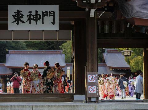Kimono-clad women wearing face masks to protect against the spread of the coronavirus pose for a selfie while visiting a Shinto Shrine as they celebrate Coming-of-Age, turning 20 years old, the traditional age of adulthood in Japan, Monday, Jan. 11, 2021, in Tokyo. Most of the city hosted ceremonies were cancelled due to a state of emergency. (AP Photo/Kiichiro Sato)