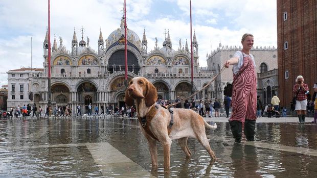 People walk on a catwalk at the flooded St. Mark's Square during a period of seasonal high water in Venice, Italy, October 5, 2021. REUTERS/Manuel Silvestri