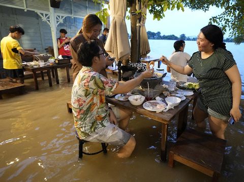 Customers of the riverside Chaopraya Antique Café enjoy themselves despite the extraordinary high water levels in the Chao Phraya River in Nonthaburi, near Bangkok, Thailand, Thursday, Oct. 7, 2021. The flood-hit restaurant has become an unlikely dining hotspot after fun-loving foodies began flocking to its water-logged deck to eat amid the lapping tide. Now, instead of empty chairs and vacant tables the “Chaopraya Antique Café” is as full as ever, offering an experience the canny owner has re-branded as “hot-pot surfing.” (AP Photo/Sakchai Lalit)